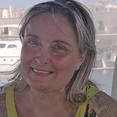 A white woman with blonde hair photographed outdoor.